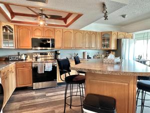 une cuisine avec des placards en bois et un grand îlot avec des tabourets de bar dans l'établissement Penthouse Shores 307, à Clearwater Beach