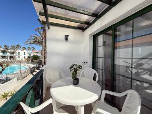 a white table and chairs on a balcony with a pool at Oceanica home in Mogán