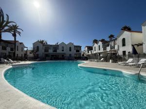 a large swimming pool with chairs and buildings at Oceanica home in Mogán