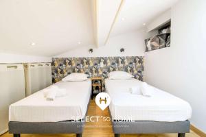 two beds in a room with white walls at SELECTsoHOME - Cocon avec jardin, plancha et parking privé ! - Résidence avec piscine et tennis - CASITA in Bormes-les-Mimosas