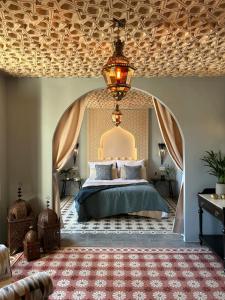 a bedroom with a large bed and a chandelier at Casa Alamanda Moclin in Moclín