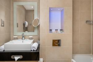 Un baño con lavabo, espejo y bañera. en Washington Mayfair Hotel, en Londres 33 fotos más