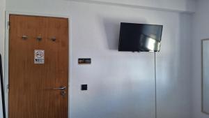 a flat screen tv on a wall next to a door at Pescadores GuestHouse in Costa da Caparica +23 photos