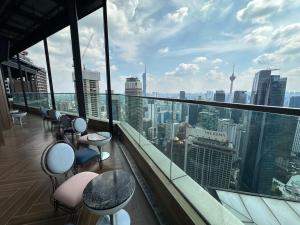 a balcony with chairs and tables and a view of the city at Ikon Service Apartment at IMPERIAL in Kuala Lumpur