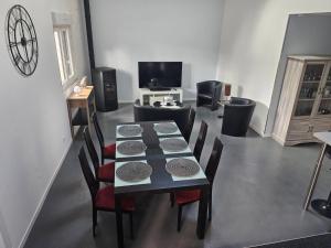 a dining room with a table and chairs and a television at Gîte Le Carré 17 in Lillers