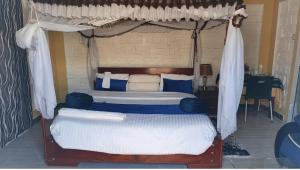 a bedroom with a canopy bed with white and blue pillows at Sandfields Lodwar Resort and Spa in Lodwar