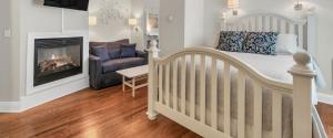 a bedroom with a crib and a chair and a fireplace at Tandem Bike Inn in Belmar