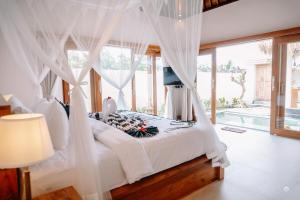 una camera da letto con letto e tende bianche di NaSya Villa Ubud ad Ubud Altre 86 foto