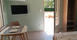 a room with a table and a television and a bed at Studio bois du bournat piscine et tranquilité in Saint-Avit-Sénieur