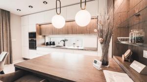 a kitchen with a wooden table and two lights at LuxHome by Lake Neusiedl with Jakuzzi in Fertőszentmiklós