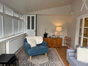 a living room with a blue chair and a table at The Corner House, 36, Broadway Road, in Evesham