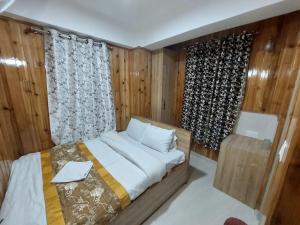 a bedroom with a bed and a window with curtains at Hotel Rashak in Gangtok