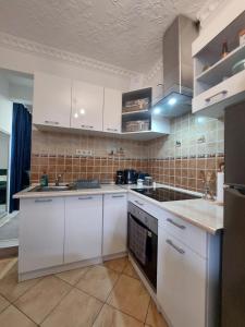 a kitchen with white cabinets and a stove top oven at Akácvirág Airport Bogi Apartman in Debrecen