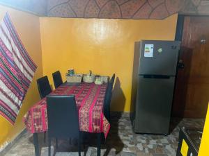 a table with chairs and a refrigerator in a room at Estrella Ancestral 1 in San Pedro de Atacama