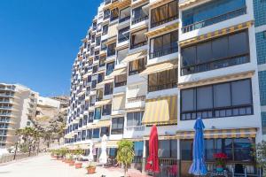 a tall building with umbrellas in front of it at Seafront Studio in Patalavaca