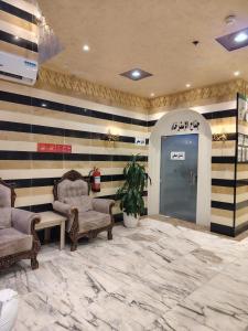 a lobby with striped walls and two chairs and a door at AL Tamayoz Alraqi - Hira branch in Jeddah
