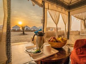 a table with a bowl of fruit and a plate of food at Desert Heritage Sam Camps & Resort in Jaisalmer