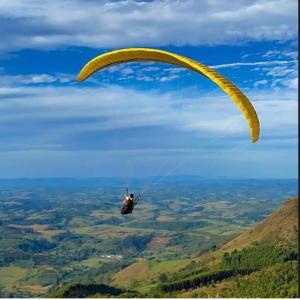 a person riding a parachute in the sky at Living in Poços de Caldas