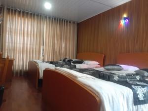 two beds in a room with wooden walls at Happy inn in Nuwara Eliya