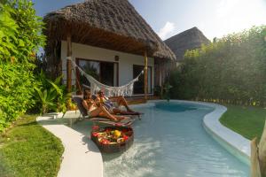 three women sitting in a hammock in a swimming pool at Safaya Luxury Villas - Adults only in Nungwi