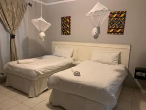 two beds in a room with white sheets and lights at LePatino BnB in Livingstone