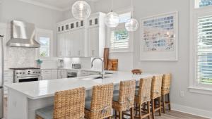 eine Küche mit Spüle und Theke mit Stühlen in der Unterkunft Gulf-View Retreat w Rooftop Deck, Private Pool Villa Anesi by AvantStay in Santa Rosa Beach