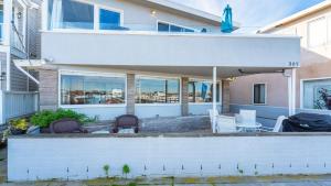 a patio with chairs and a table in front of a house at Coastal Bayside Condo Walkable to Sand Surf in Newport Beach