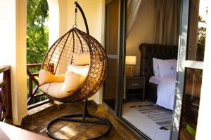a hanging chair with pillows on a balcony at Manaya Luxury Sunset & Serenity Serviced 2Bedroom by Diani Beach with Pool & Parking in Galu