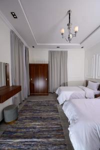 a bedroom with two white beds and a piano at منتجع حياه رويال الطائف in Ash Shuwaybiţ