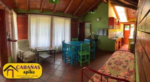 Una sala de estar con una mesa y una cocina. en Cabañas Apiku, Lago Puelo, en Lago Puelo