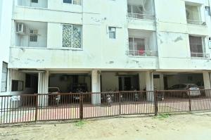 Un edificio blanco con coches aparcados delante. en JD Homestays, en Jaipur