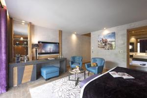 a hotel room with a bed and two blue chairs at MGM Hôtels & Résidences - Hôtel Les Suites d'Alexane in Samoëns