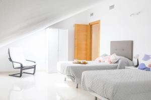 a white room with two beds and a chair at NT Bright and modern apartment in Pizarra in Pizarra