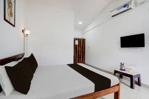 a white bedroom with a bed and a tv at Hotel O fenni and ferns stays in Anjuna +21 photos