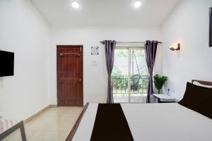 a bedroom with a bed and a large window at Hotel O fenni and ferns stays in Anjuna