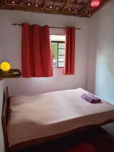 a bed in a room with two red curtains at Casinha christinense in Cristina +19 photos