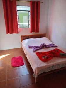 a bedroom with a bed with red curtains and a window at Casinha christinense in Cristina