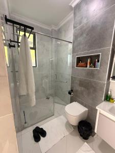a bathroom with a glass shower and a toilet at Serian Breeze Villa in Ukunda