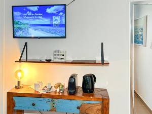 a television hanging on a wall with a wooden table at Deluxe Boutique Apartments Sonrisa - Adults only in Kralendijk