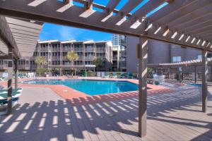 a swimming pool with a bench and a building at Tilghman Beach & Racquet Club - 114 in Myrtle Beach