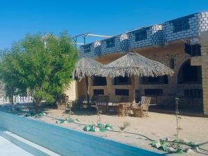 a building with a table and a straw umbrella at agyptus camp in Siwa