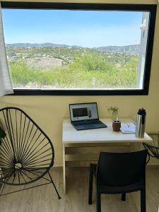 a desk with a laptop and a chair in front of a window at Casa Carlos Paz, 6 personas in Estancia Vieja