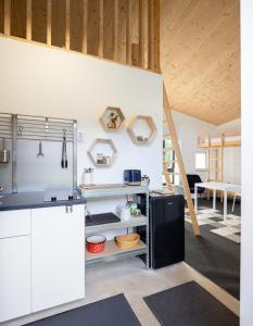 Una cocina con gabinetes blancos y un refrigerador negro. en Hypha etc, en Cîmpu Cetăţii 15 fotos más