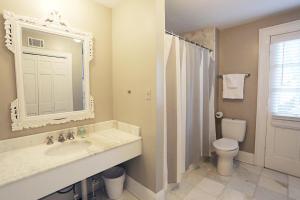 a bathroom with a sink and a toilet and a mirror at Oglethorpe Manor Main House in Savannah +22 photos