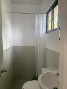 een badkamer met een wastafel en een toilet en een raam bij Whole Furnished House with Parking and Sea View in Tagibo