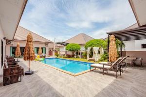 a swimming pool in a house with chairs and umbrellas at 派对家园-11卧室独栋大泳池私密别墅 in Ban Huai Yai