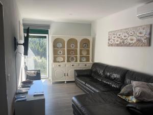 a living room with a leather couch and a window at A Casa da Azenha in Sertã