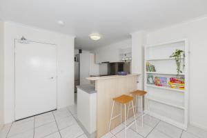 タウンズビルにあるCBD Apartment w River Views Pool & Parkingの白い壁のキッチン、カウンター&スツール