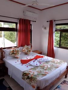 a bedroom with a large bed with red curtains at Belle Rose Vue guest house in Baie Sainte Anne