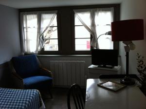 een woonkamer met een tafel, een stoel en een raam bij L'appartement au-dessus du in Straatsburg